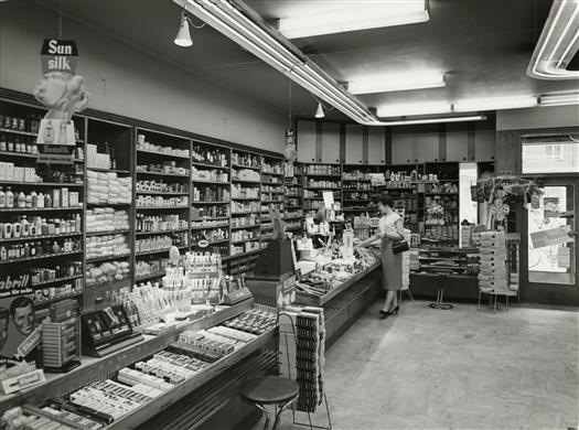 Interiör av butiken vid hörnet av Thulehuset mot Tunnelgatan. Kassan med varor och kund.