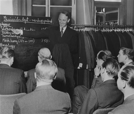 Lektion i NK-skolan. Eleverna undervisas i minimibudget för en vardagsgarderob med herrkläder.